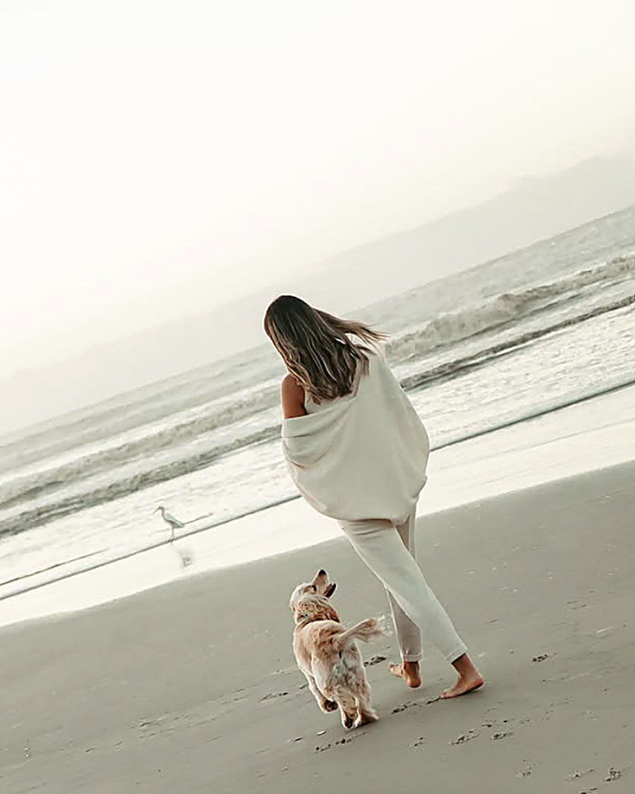Mulher correndo na praia com o cachorro