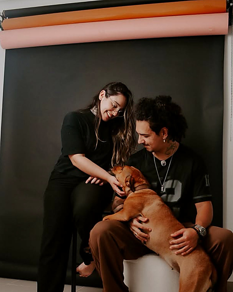 Casal com cachorro em estúdio, fundos coloridos ao fundo