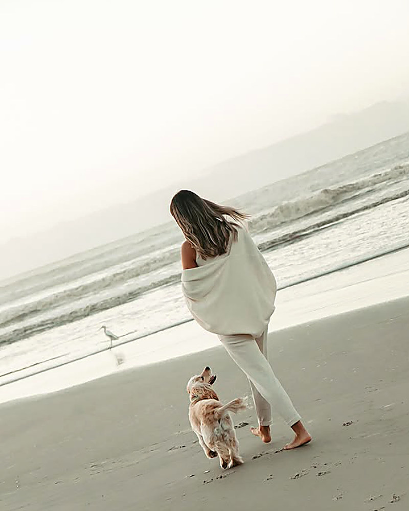 Mulher correndo na praia com cachorro