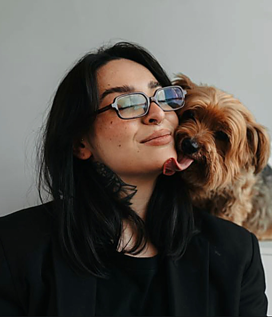 Emili Luizi sendo lambida por um cachorro pequeno de pelagem clara